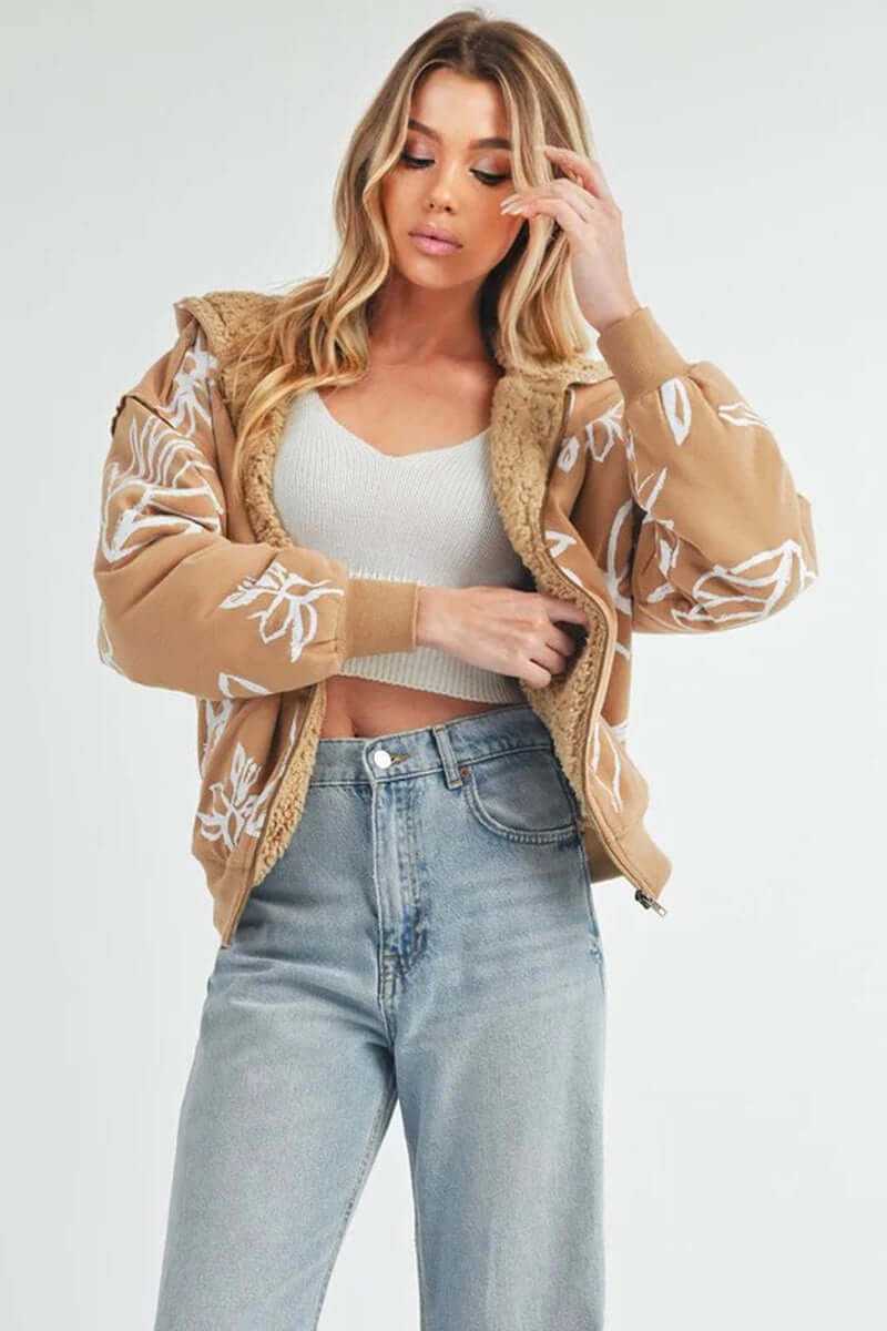 Stylish woman wearing Oita jacket with floral details, sherpa lining, and oversized fit, paired with high-waisted jeans.