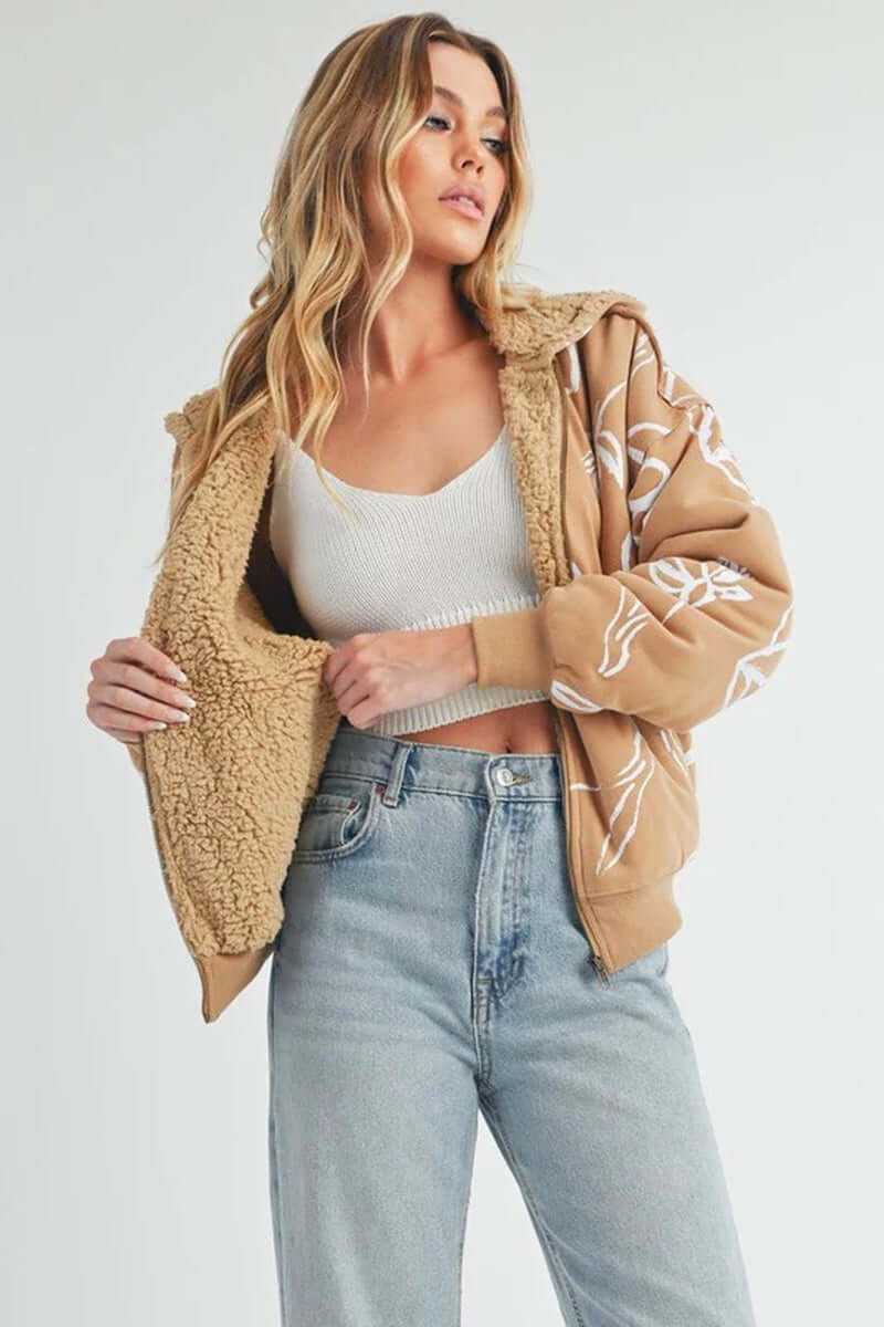 Model wearing the cozy Oita jacket with a hood and sherpa lining, paired with high-waisted jeans and a crop top.