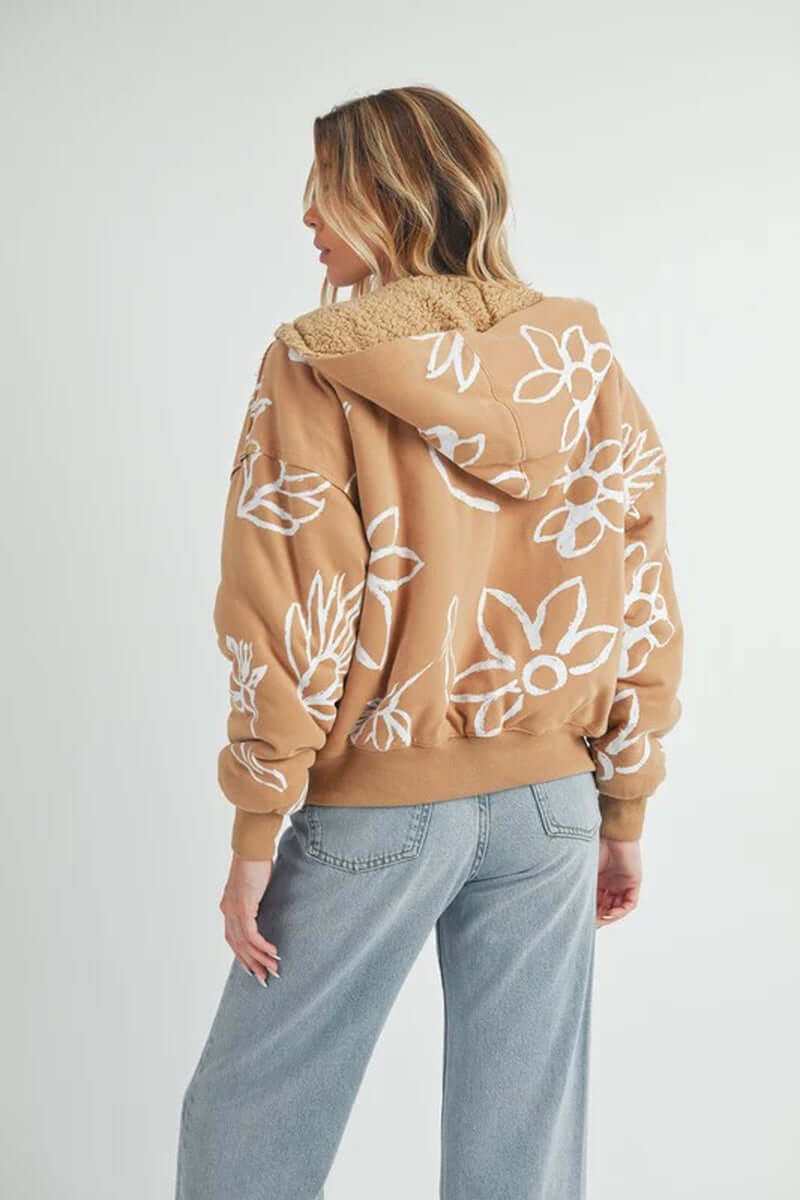 Back view of a woman in a floral Oita jacket with a hood, soft sherpa lining, and dropped shoulders, styled casually.