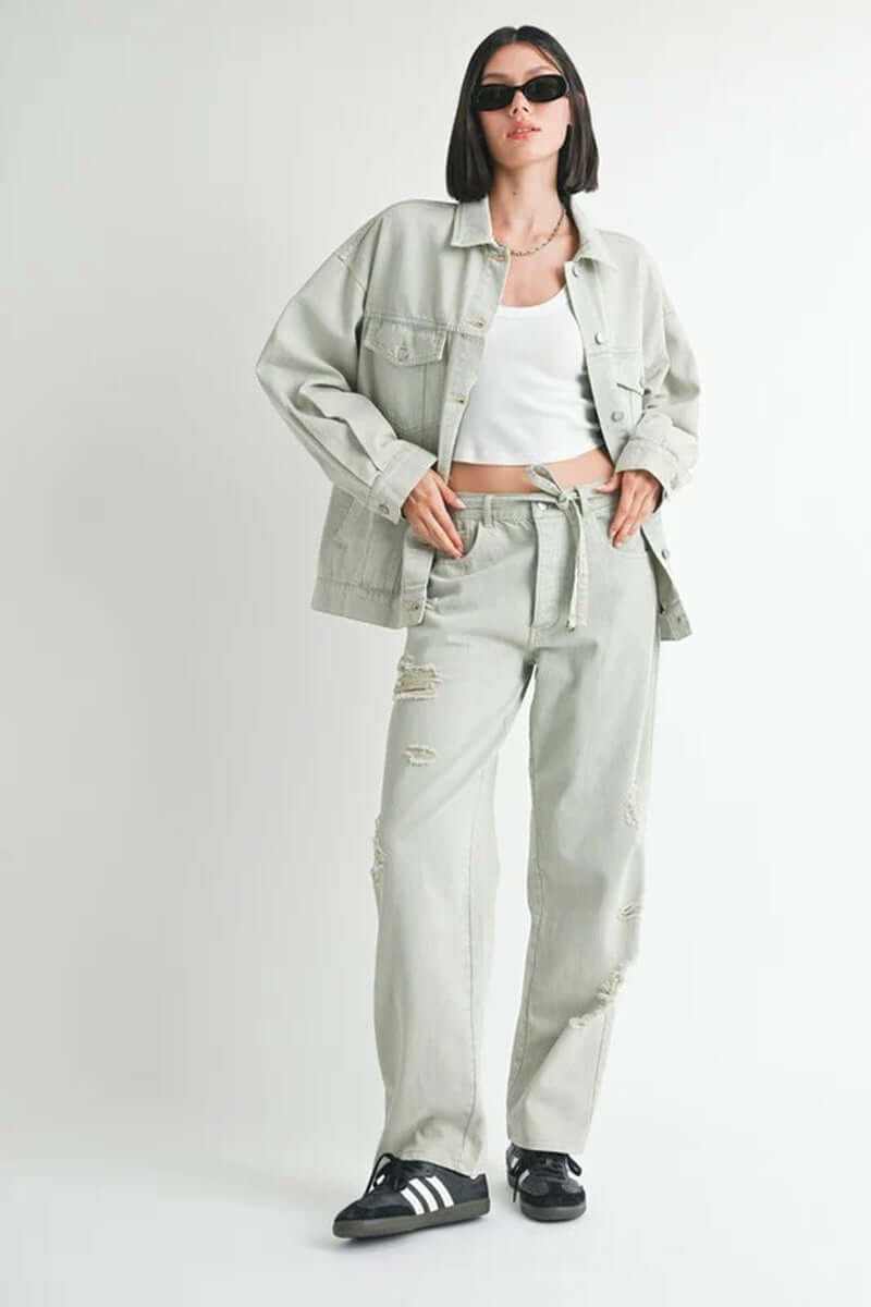 Model wearing an oversized denim jacket with a white top and distressed pants, showcasing casual street style.