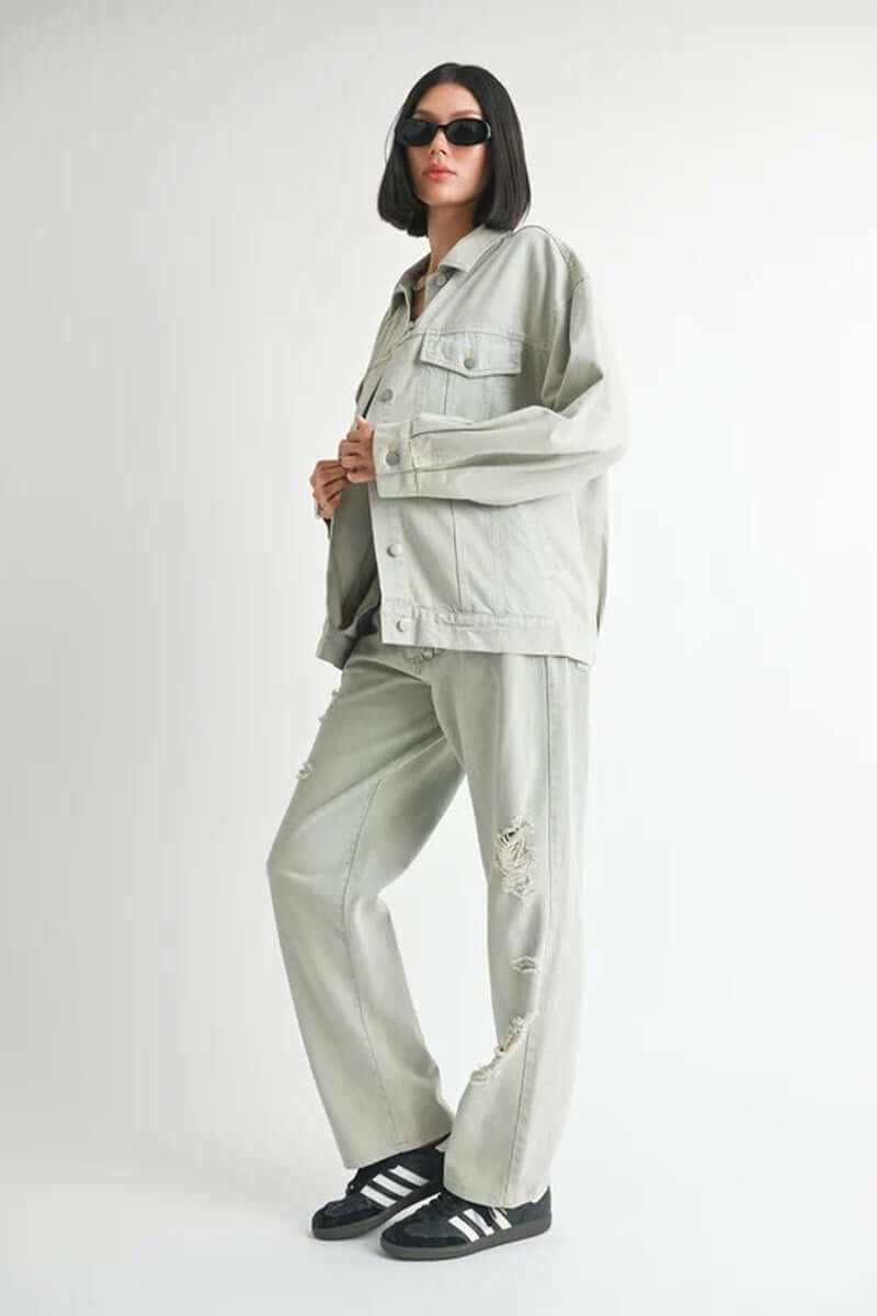 Oversized denim jacket model wearing size small, paired with gray pants and sunglasses, showcasing casual style.
