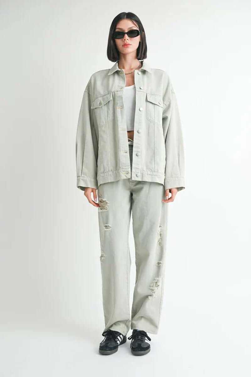 Oversized denim jacket styled with distressed pants, model wearing sunglasses and a cropped top, height 5'9.