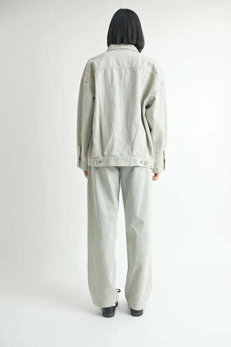 Model wearing a gray oversized denim jacket and matching pants, showcasing a casual yet stylish back view.