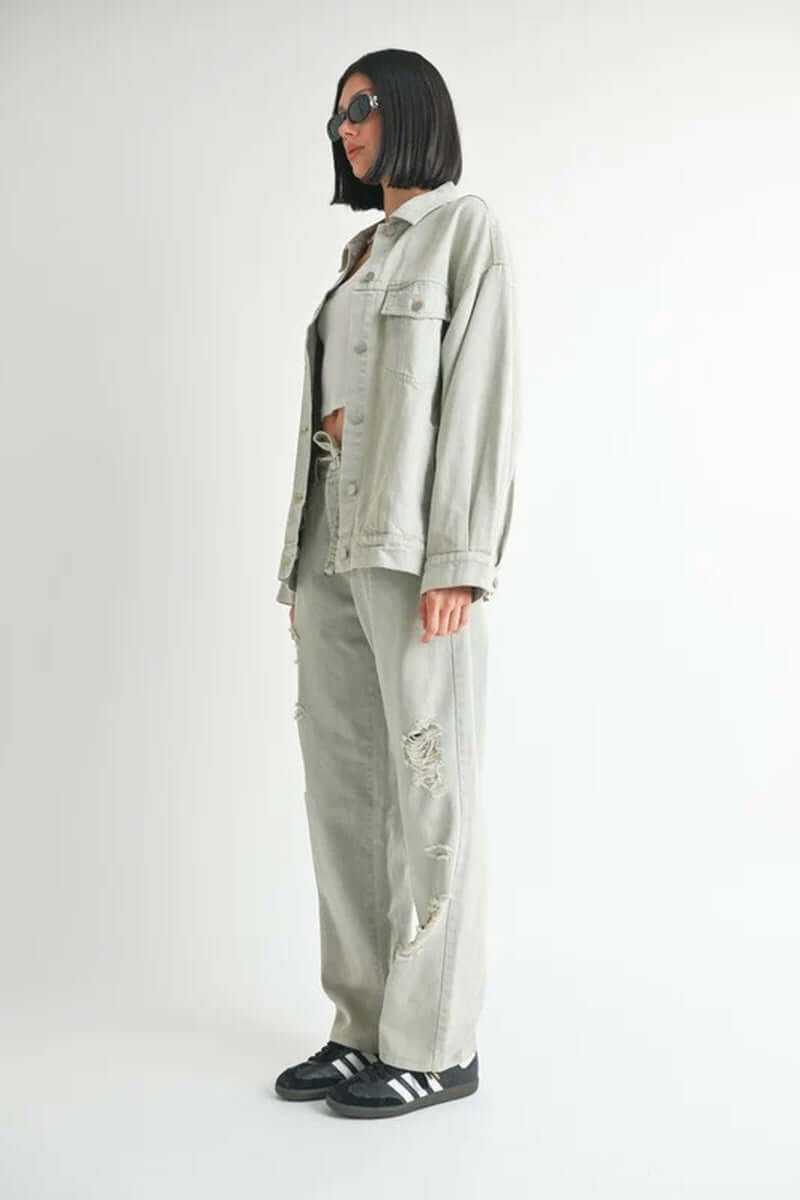 Model wearing oversized denim jacket with ripped pants, showcasing trendy streetwear style, emphasizing comfort and casual fashion.