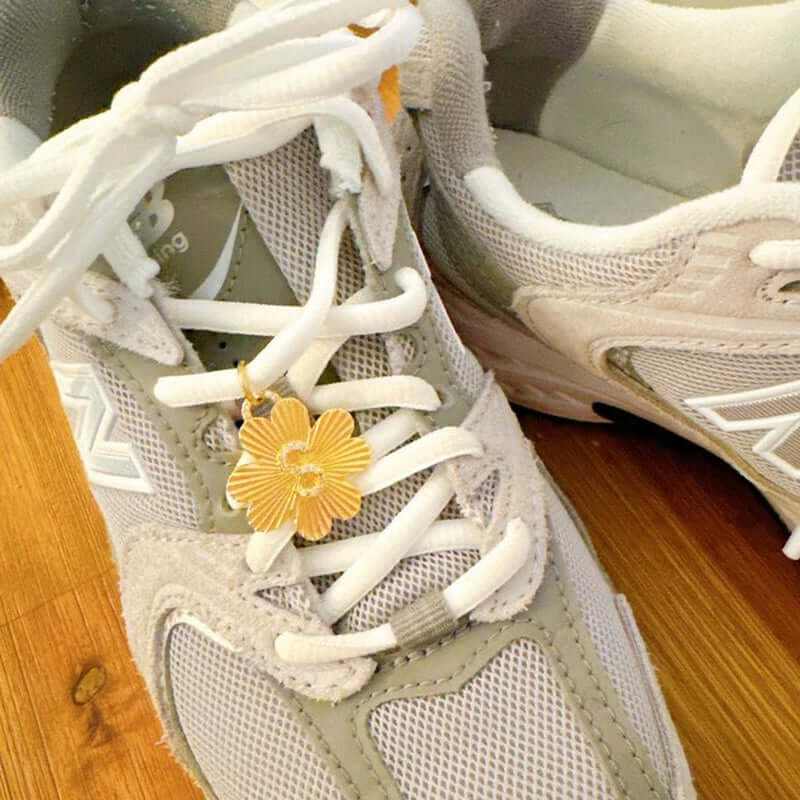 Personalized lucky clover charm clipped onto sneaker laces for stylish footwear accessorizing.