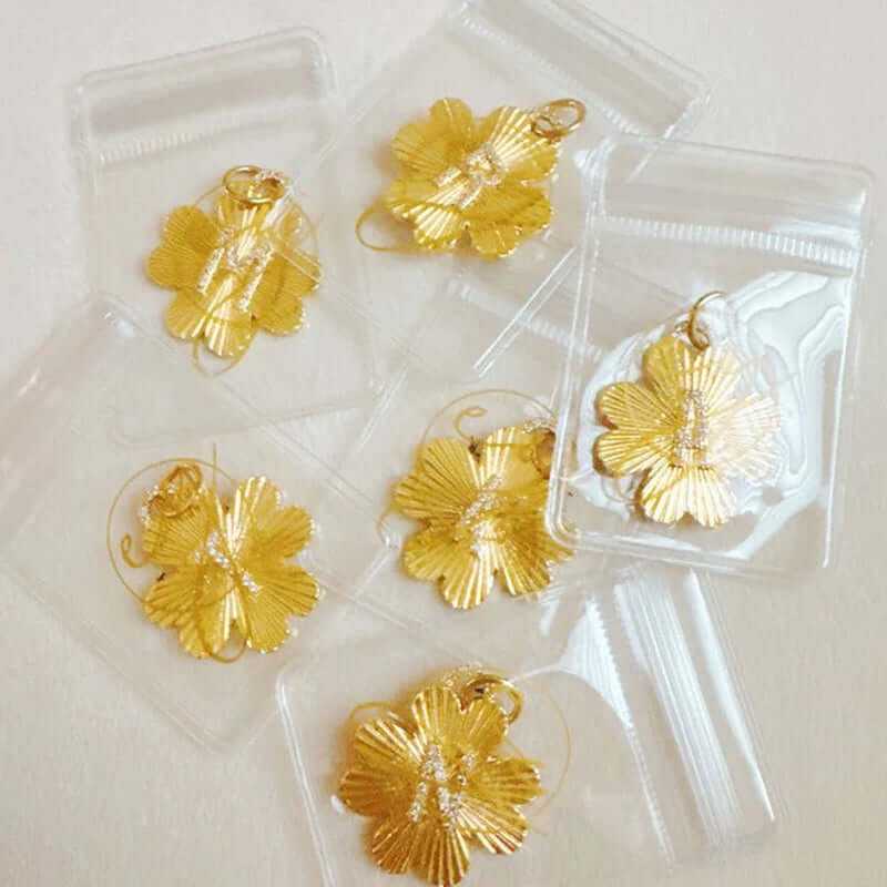 Golden clover charm clips displayed in clear packaging, perfect for personalized jewelry designs.