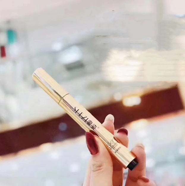 gold concealer pen for revitalizing acne and pigmentation cream held in hand with red nails