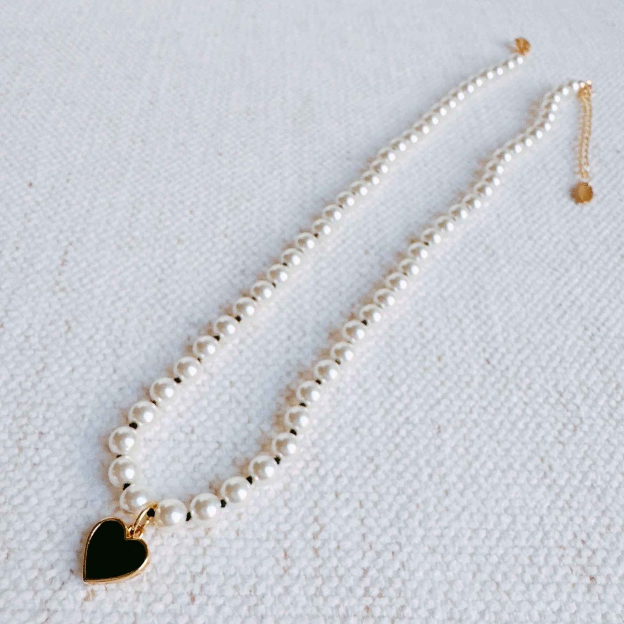 Silky adjustable thread heart pendant necklace with glass pearls and gold-plated charm, stylish accessory for any outfit.