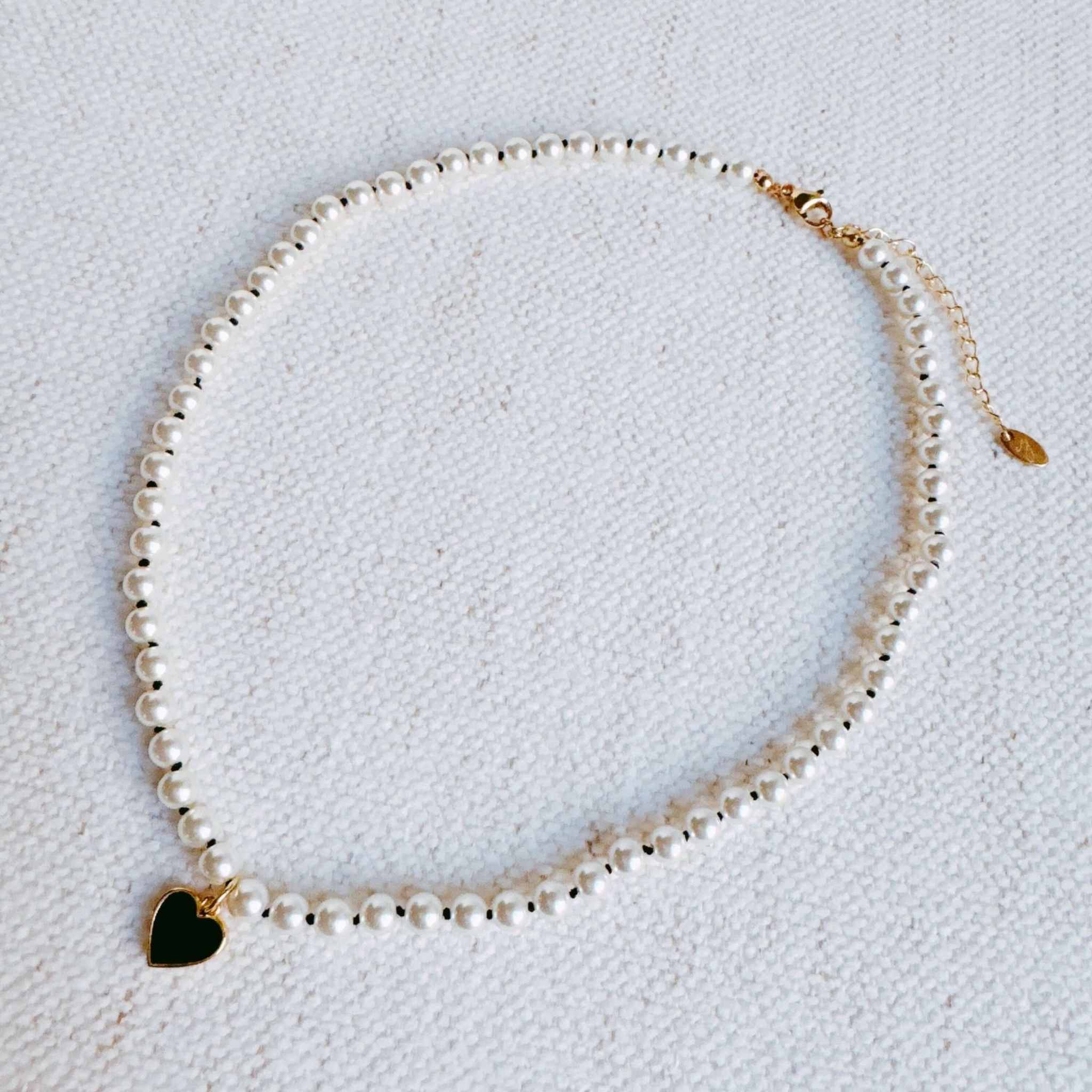 Silky adjustable thread heart pendant necklace featuring glass pearls and a gold heart charm, stylish accessory.