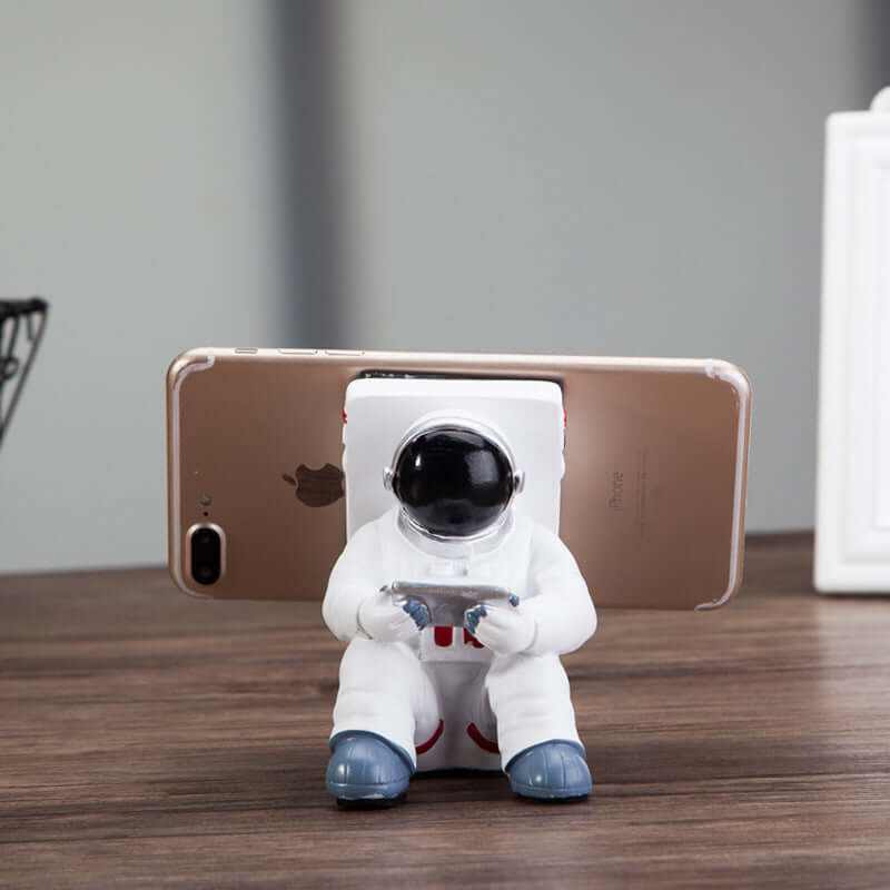 Cute astronaut mobile phone stand holding a smartphone, perfect for desk decoration and a creative gift for students.
