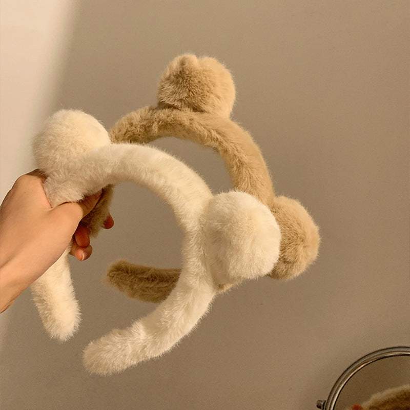 Hand holding two fluffy Spa Essential Cartoon Hair Tie headbands in milky white and khaki colors