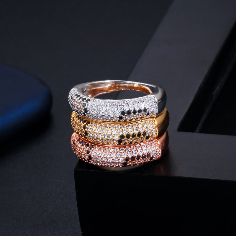 Stacked sparkling rhinestone zircon rings in platinum, gold, and rose gold colors on black background