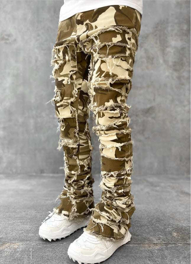 men's camo stacked jeans with ripped distressed design and white sneakers on gray background