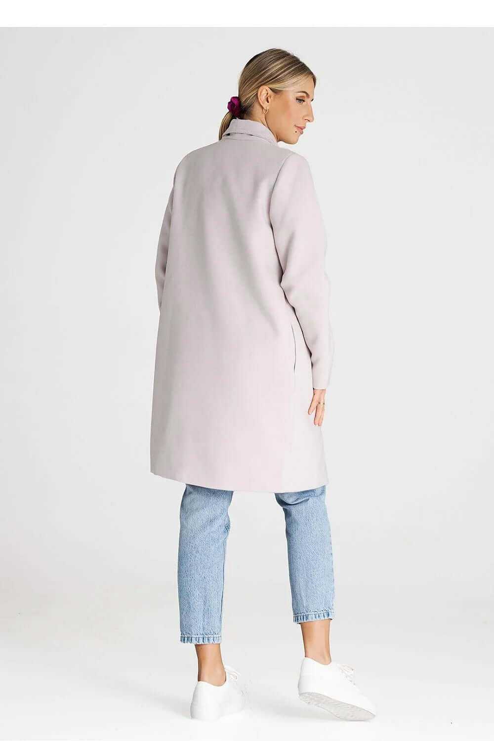 Back view of a stylish double-breasted coat in light pink, paired with jeans and white sneakers.