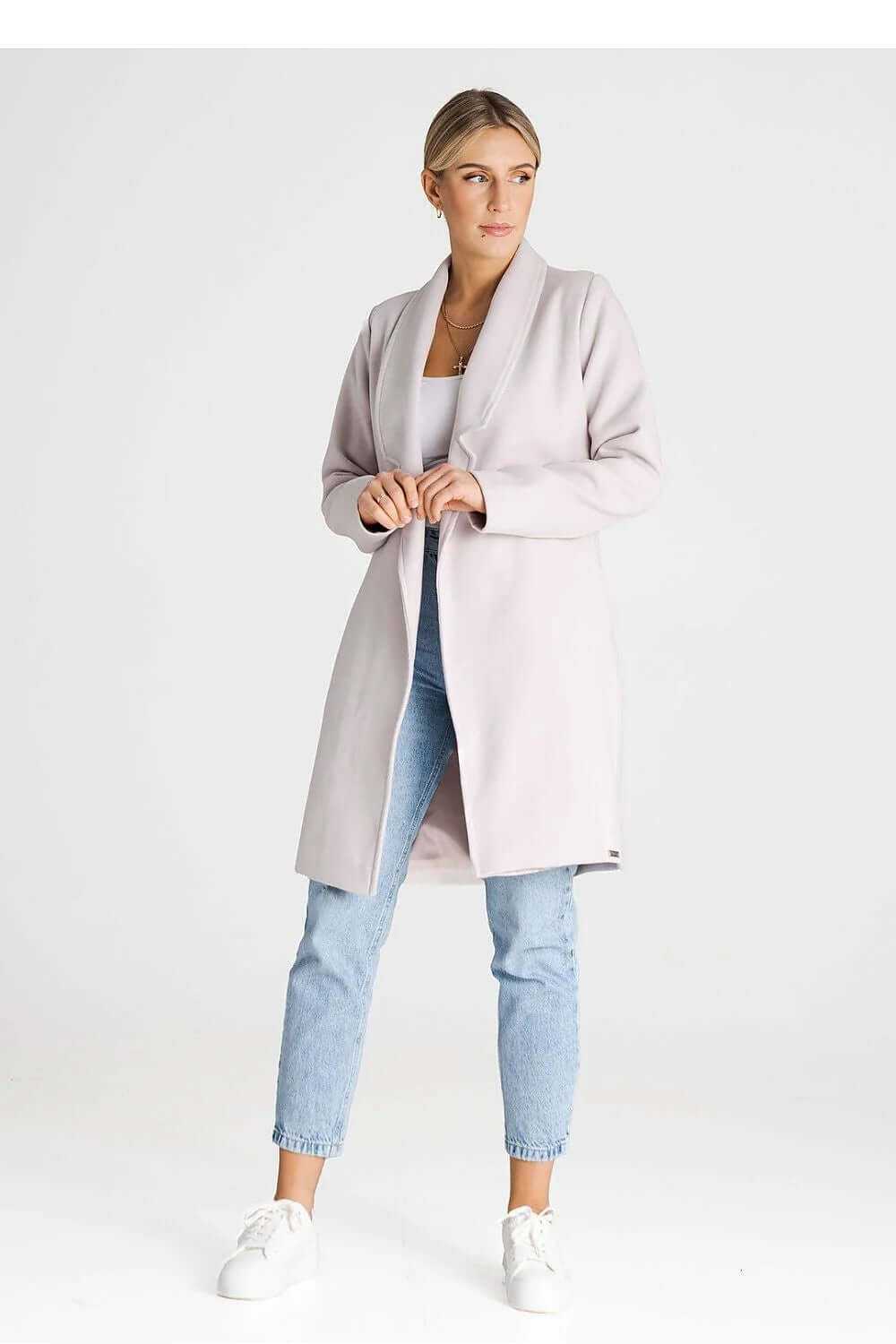 Model wearing a stylish Figl double-breasted coat in soft pink, paired with light jeans and sneakers.