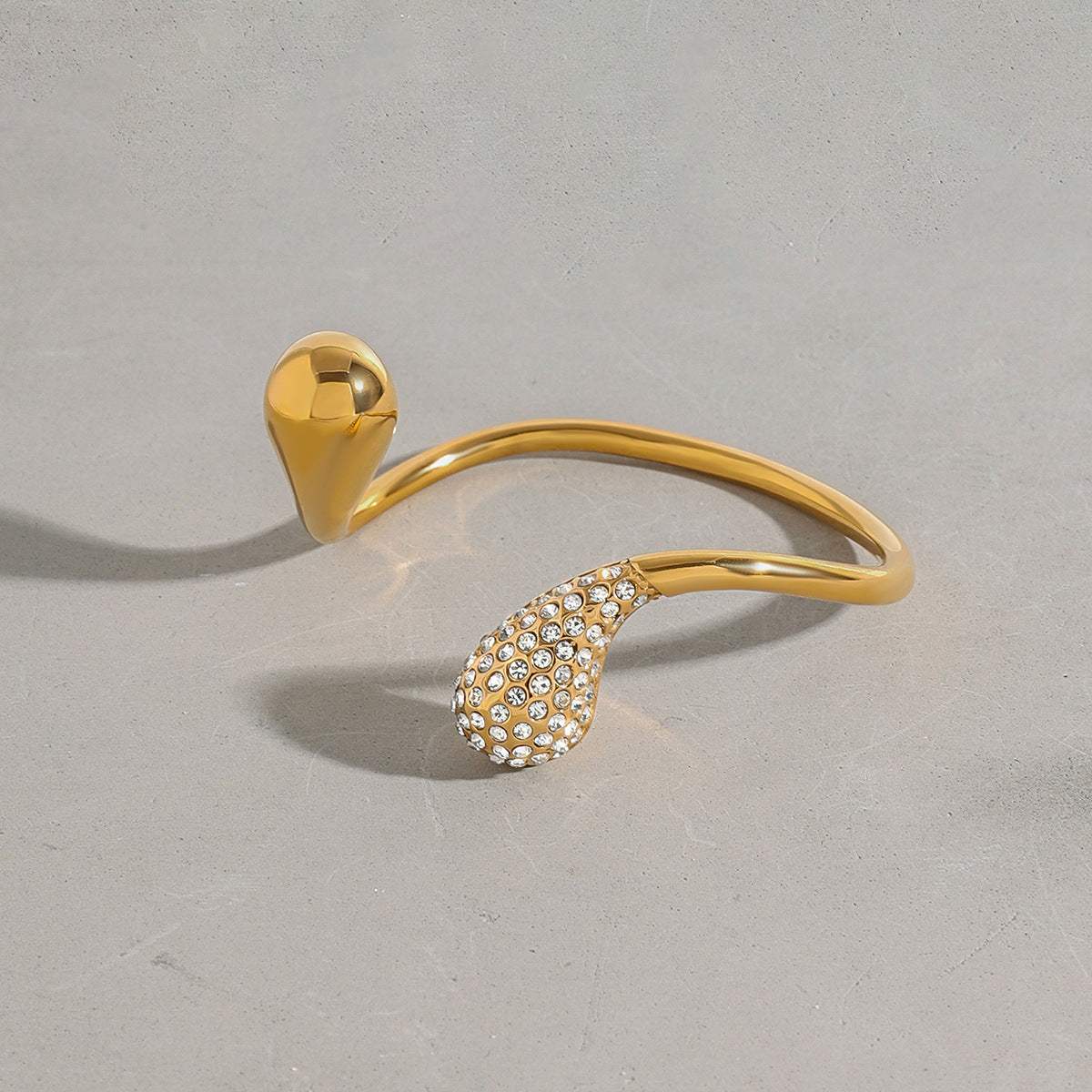 Gold titanium steel bracelet with diamond water drop design on gray background