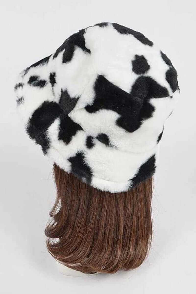 Trendy soft cow print faux fur bucket hat displayed on a mannequin with long hair.