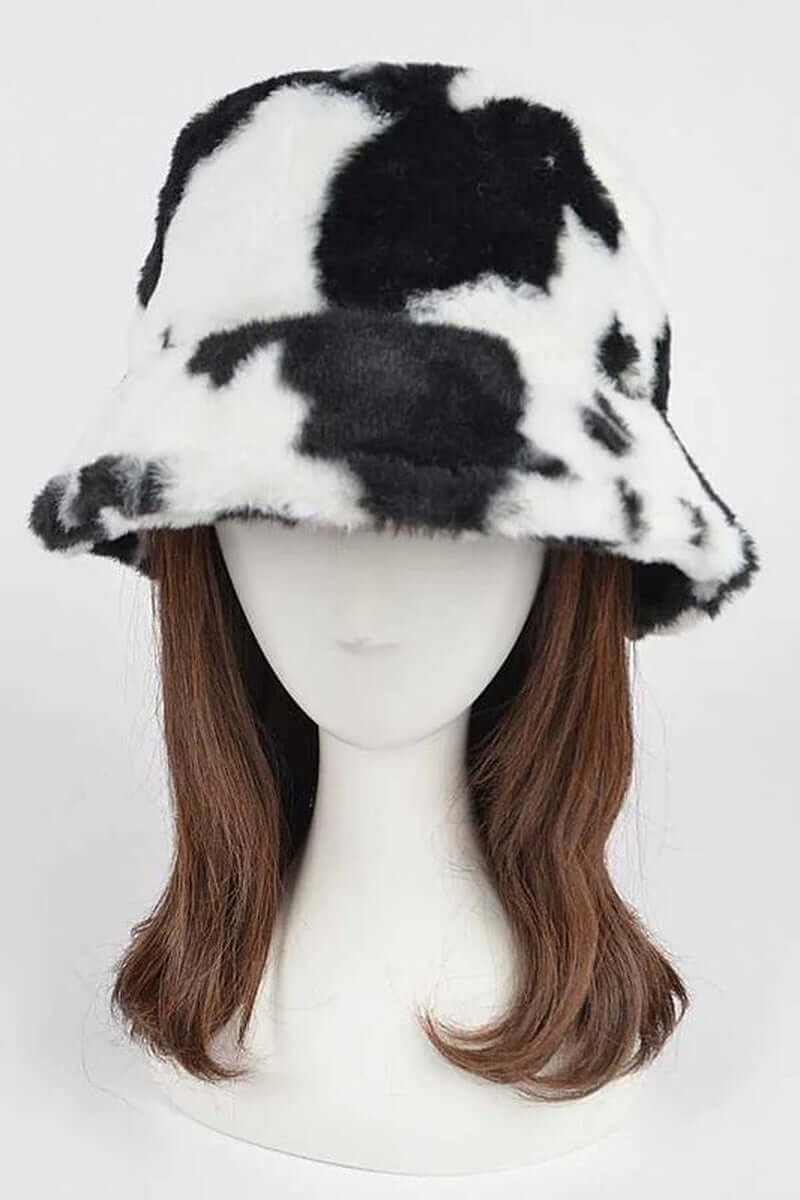 Trendy soft cow print faux fur bucket hat on a mannequin, perfect for winter street style and cozy fashion.