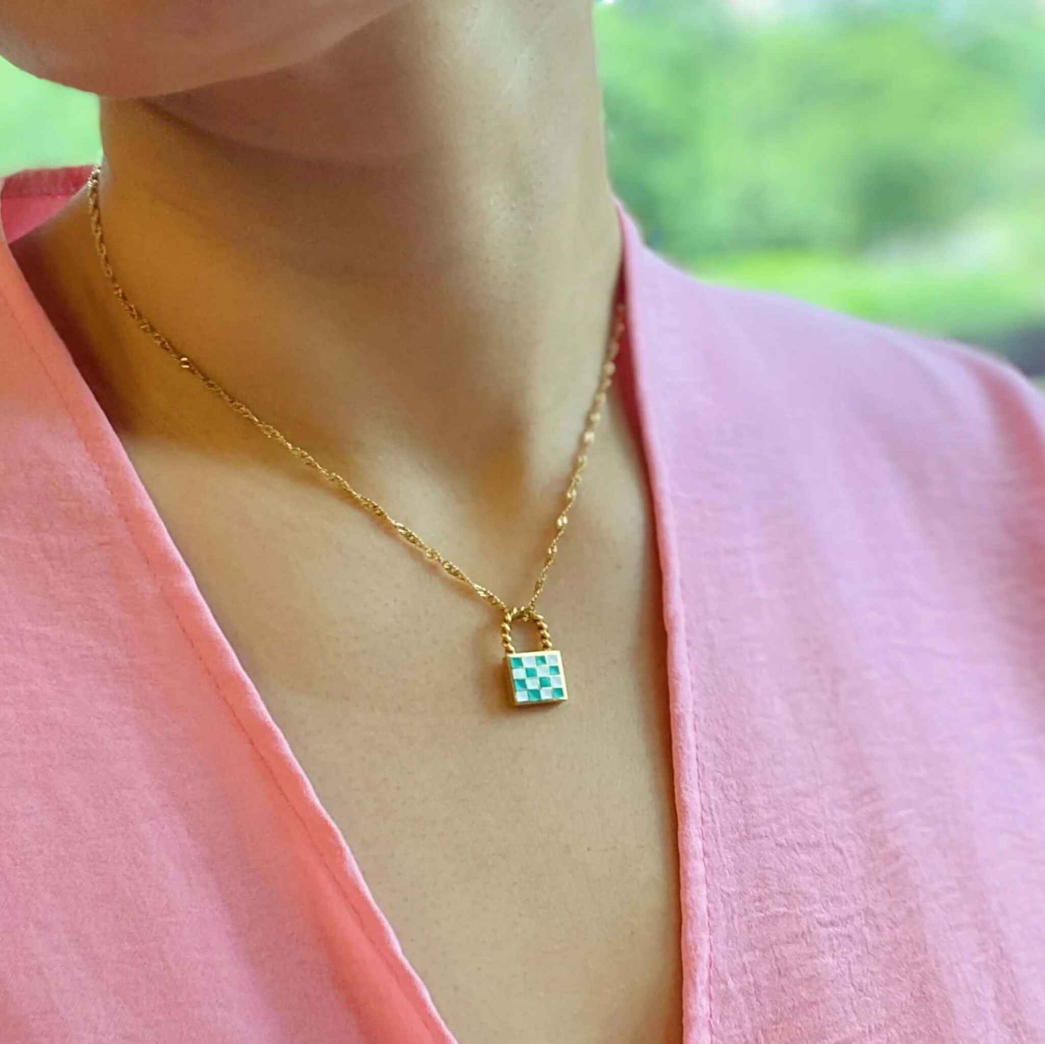 Trendy vintage checkered locket pendant necklace in gold on a model's neck, featuring a stylish checkerboard design.