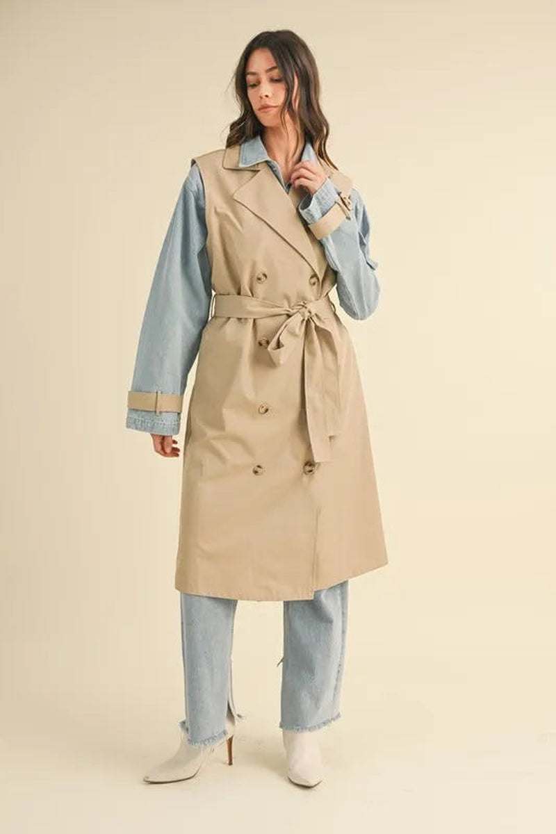 Model wearing a two-in-one MABLE layered trench coat in beige with denim sleeves for a chic, transitional outfit.