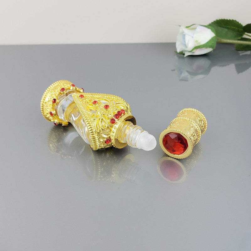 Decorative vintage cosmetic bottle with gold alloy and red stones, empty and ornate design