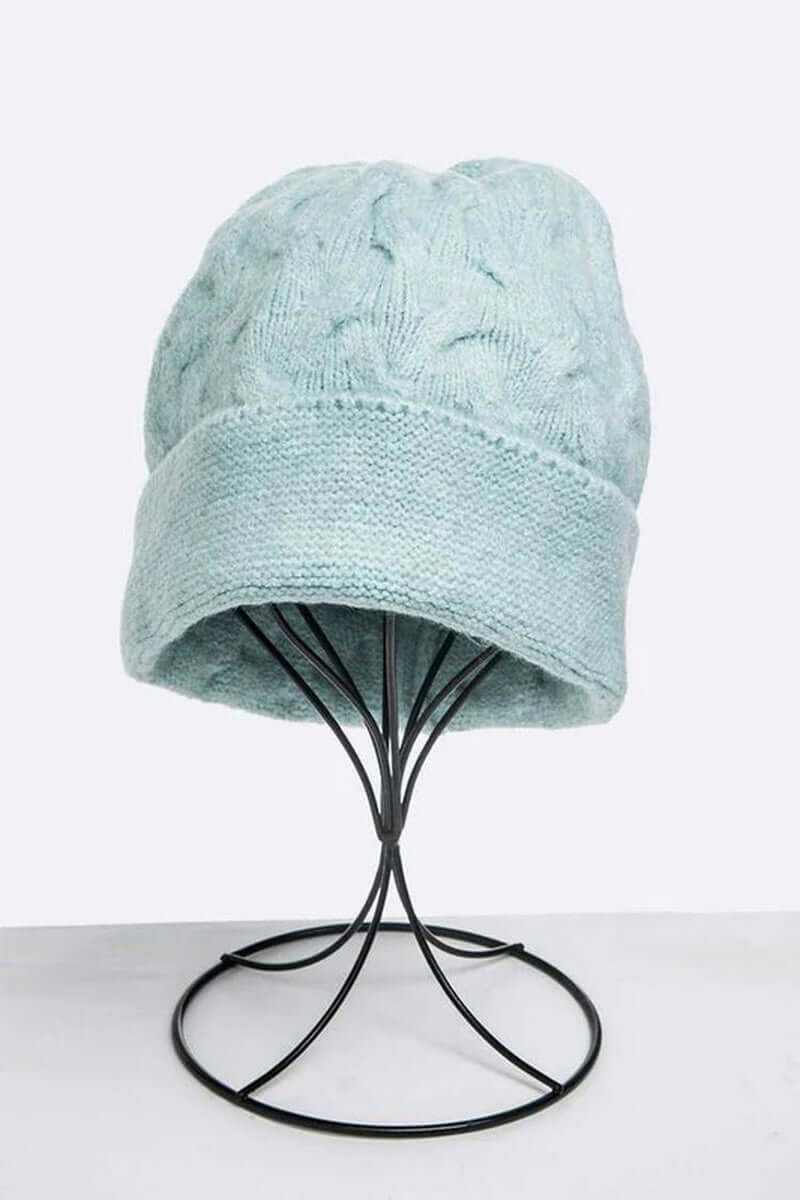 Light blue slouchy beanie hat displayed on a black headstand, featuring a cozy knit design perfect for winter.