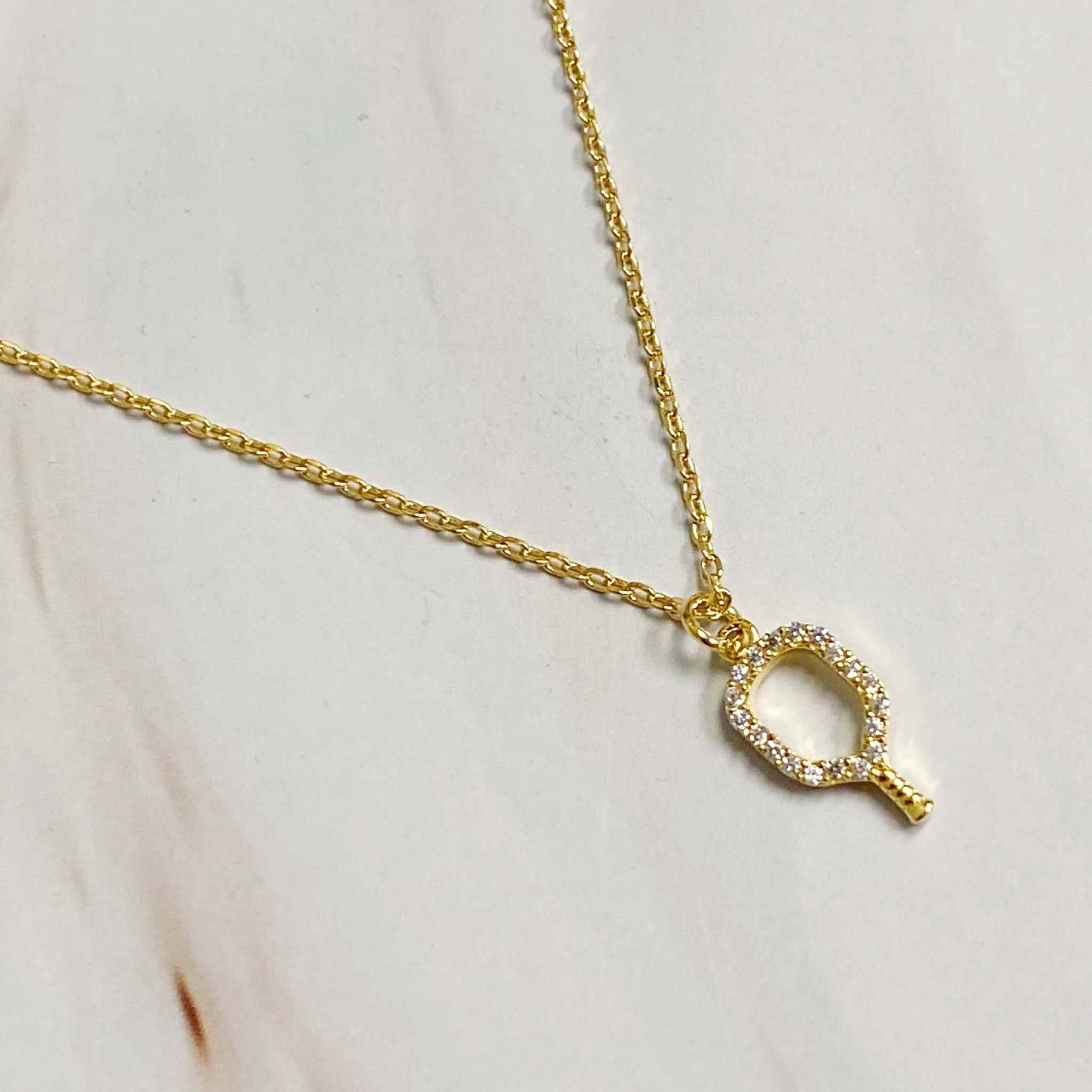 Women dainty pickleball pendant necklace featuring a gold racket outline with sparkling details.