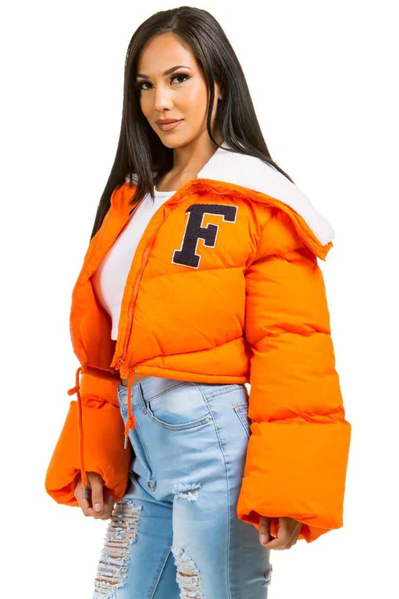 Women wearing an orange puffer teddy jacket with front zipper and oversized fit, styled with ripped jeans.