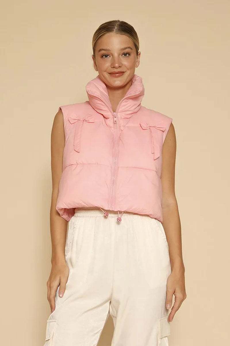 Women wearing pink cropped puffer vest with bow detailing and zipper front closure