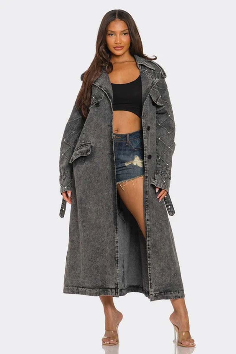 Womenβs edgy distressed longline denim trench coat with quilted sleeves and studs, styled with a crop top and shorts.