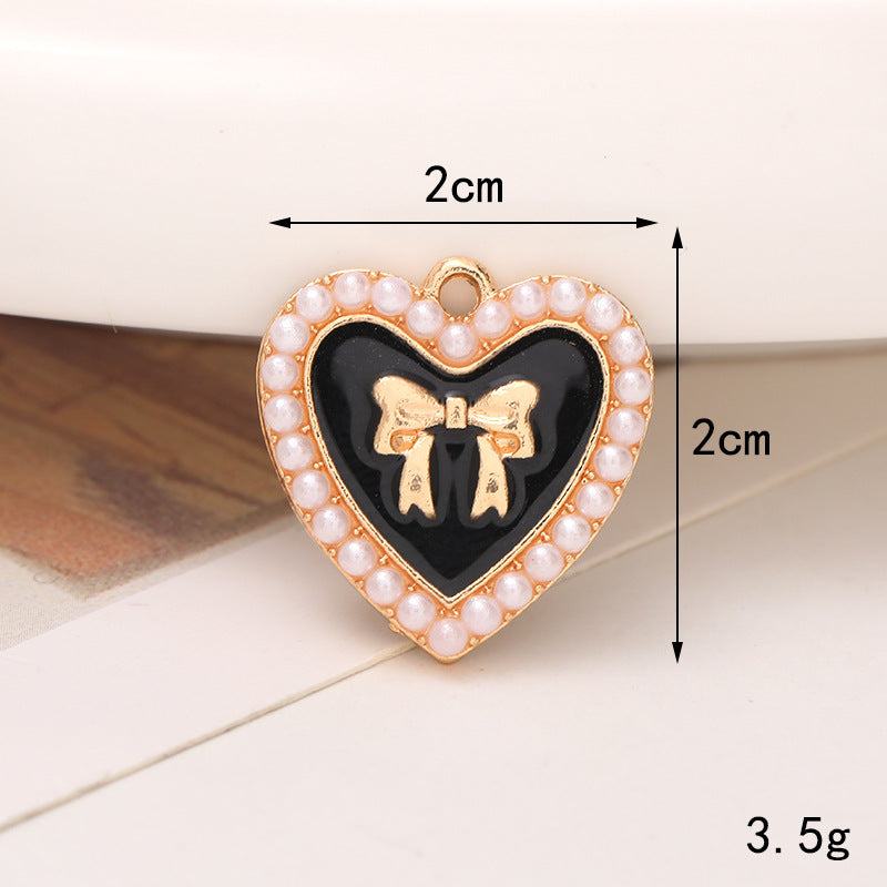 Heart-shaped shoe ornament featuring a black center, gold bow, and pearl embellishments, size 2cm.