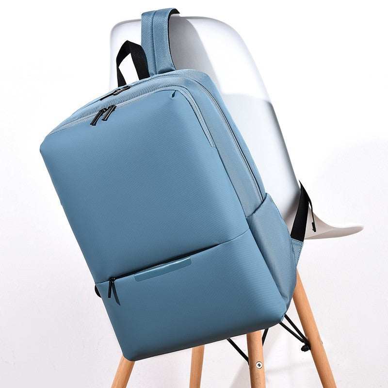 large-capacity business laptop backpack in light blue color resting on a wooden chair with a modern design.