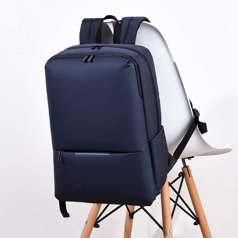Large-capacity business laptop backpack in navy color placed on a chair, featuring a sleek design and zippered compartments.