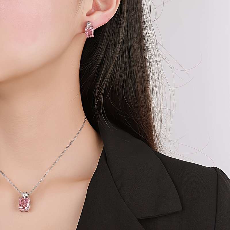 Close-up of a model wearing pink diamond earrings and necklace, showcasing elegant sterling silver design.