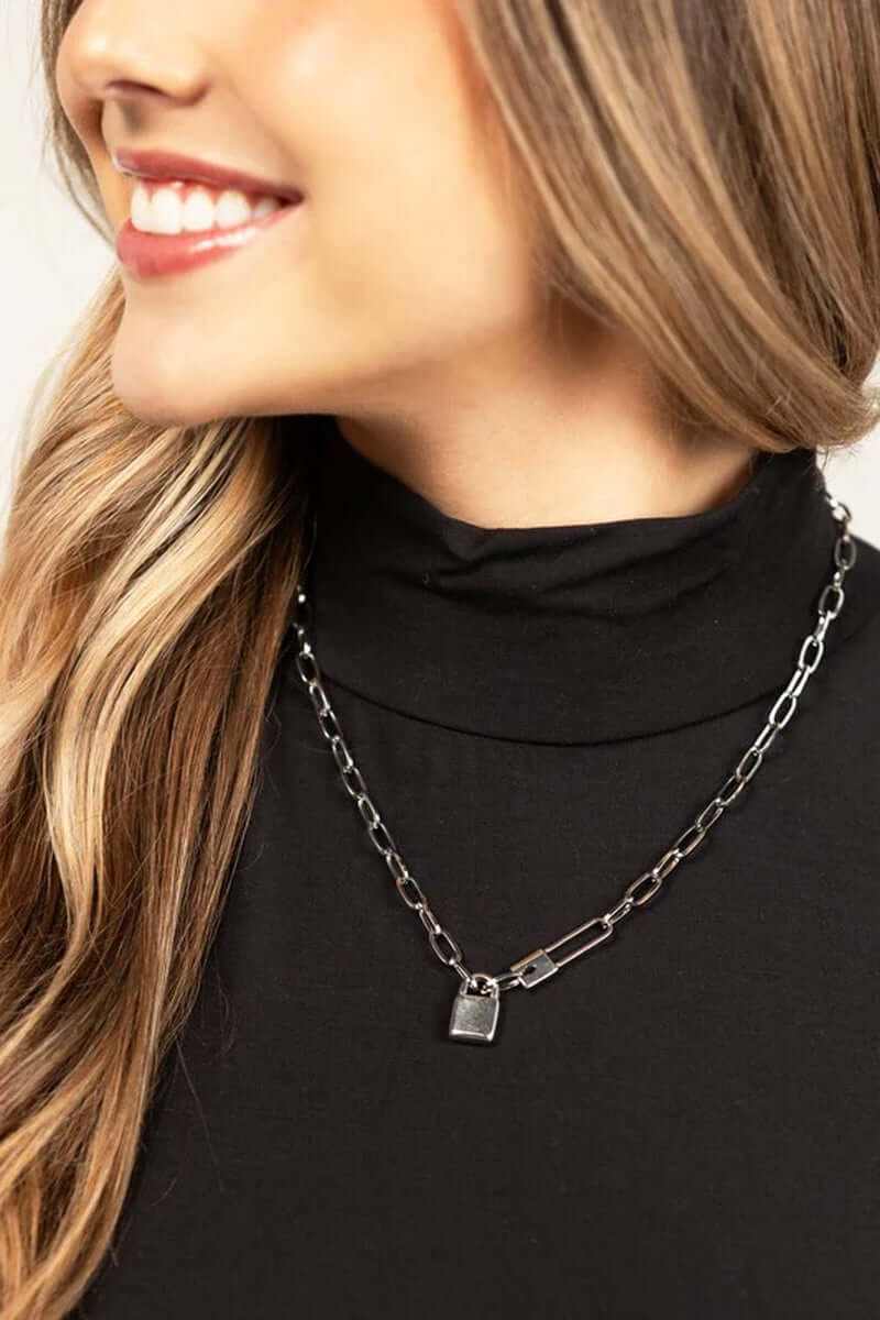 Woman wearing an 18K stainless steel lock and clip chain necklace against a black turtleneck.