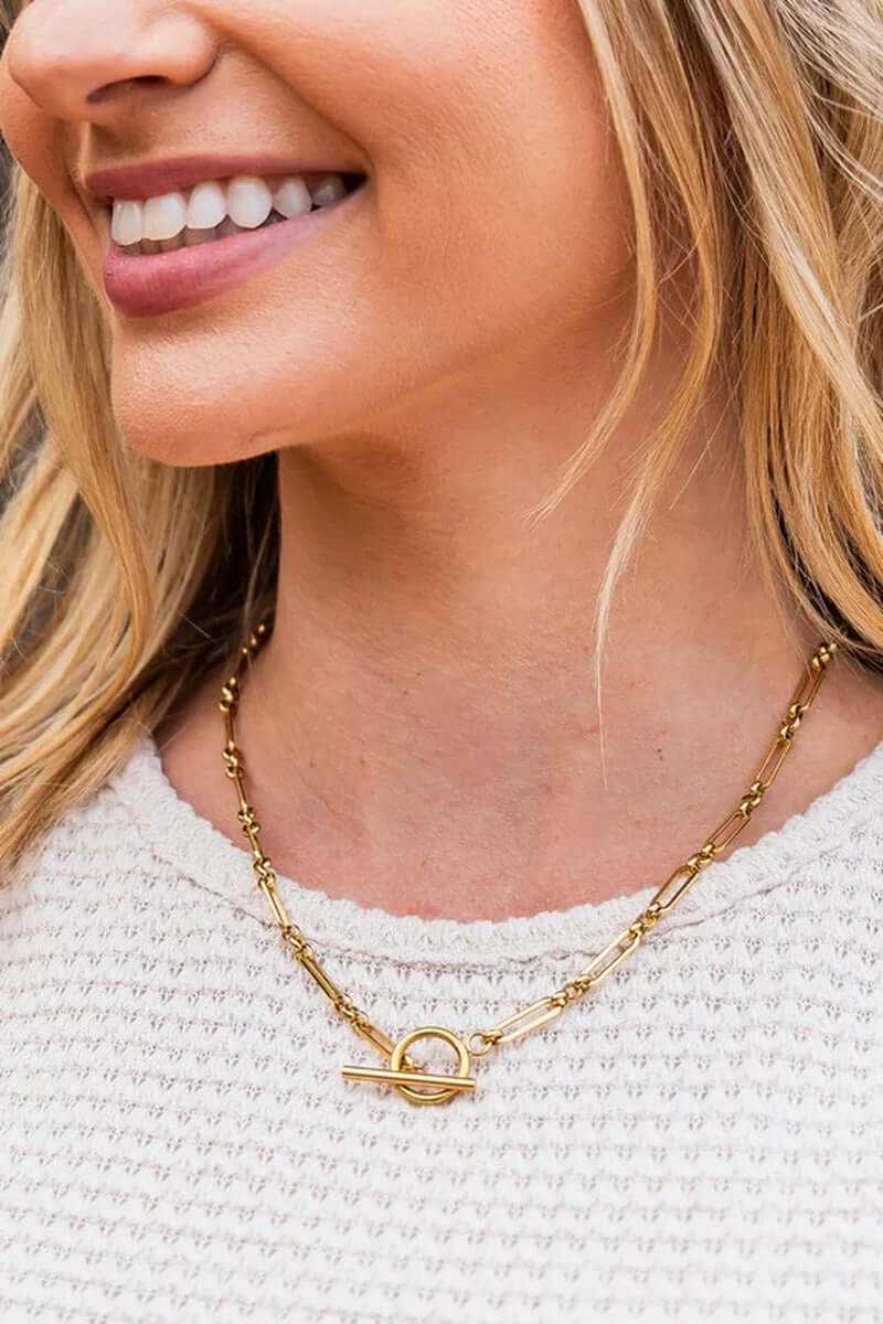 Woman wearing an 18K stainless steel toggle chain necklace, showcasing its elegant design and gold plating.