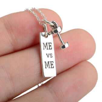 925 sterling silver dumbbell necklace with 'ME vs ME' inscription, held in hand, showcasing fitness theme and elegance.