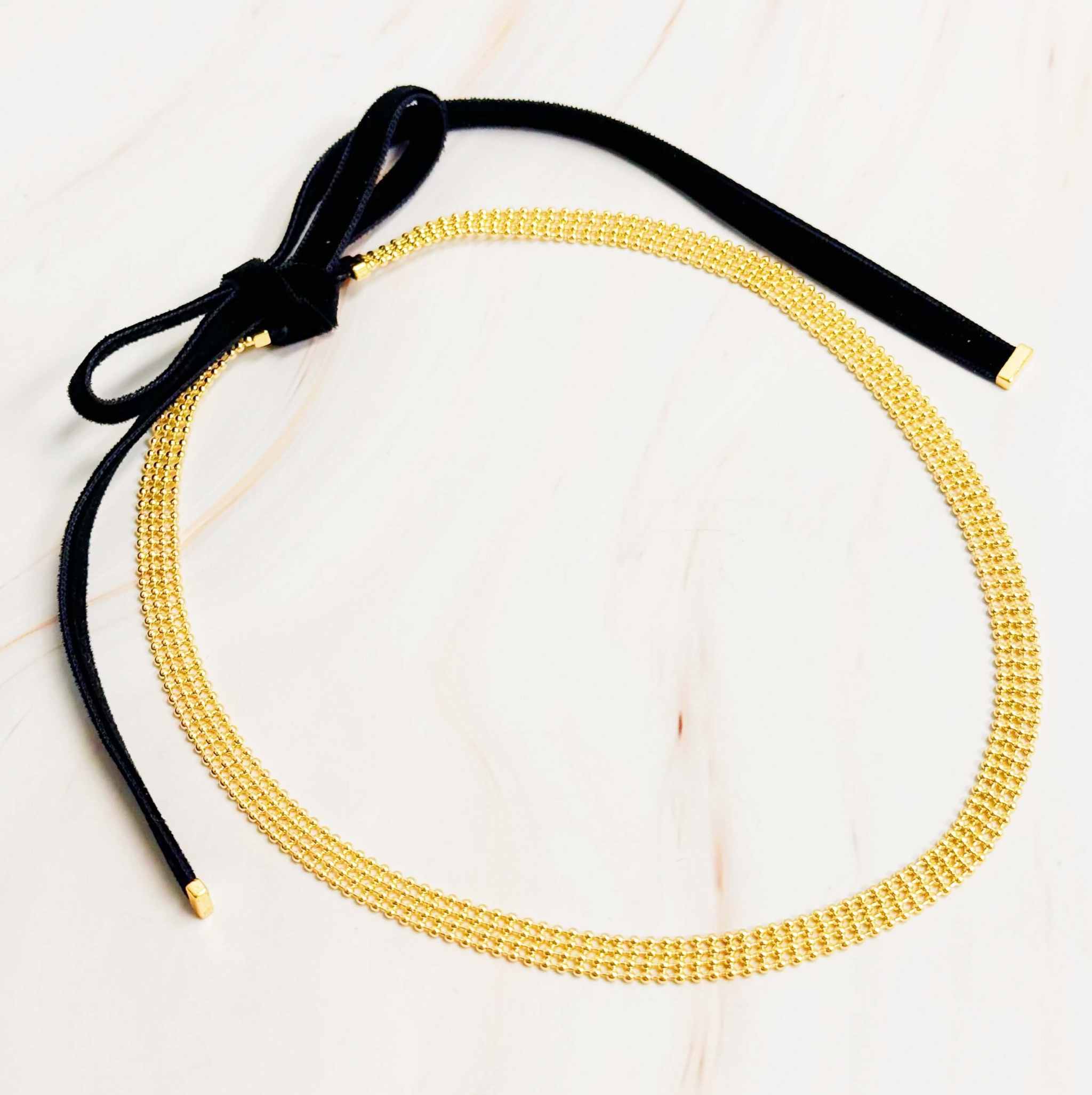 Adjustable gold tie back choker necklace with black velvety sash ties for versatile styling.