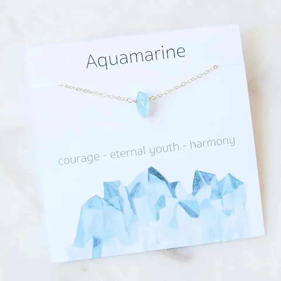 Aquamarine pendant necklace on a display card with descriptions of courage and harmony.