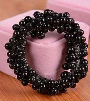 Black beaded cloth hair rope accessory on pink surface