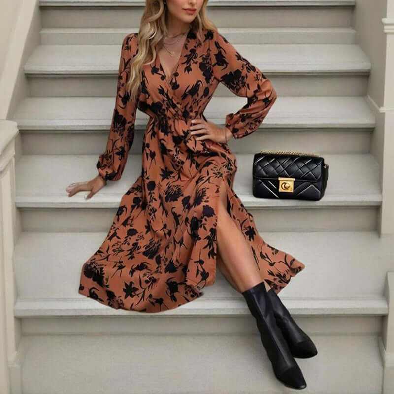 Woman in floral print V-neck maxi dress with sleeves, sitting on stairs, showcasing boho style and side slit.