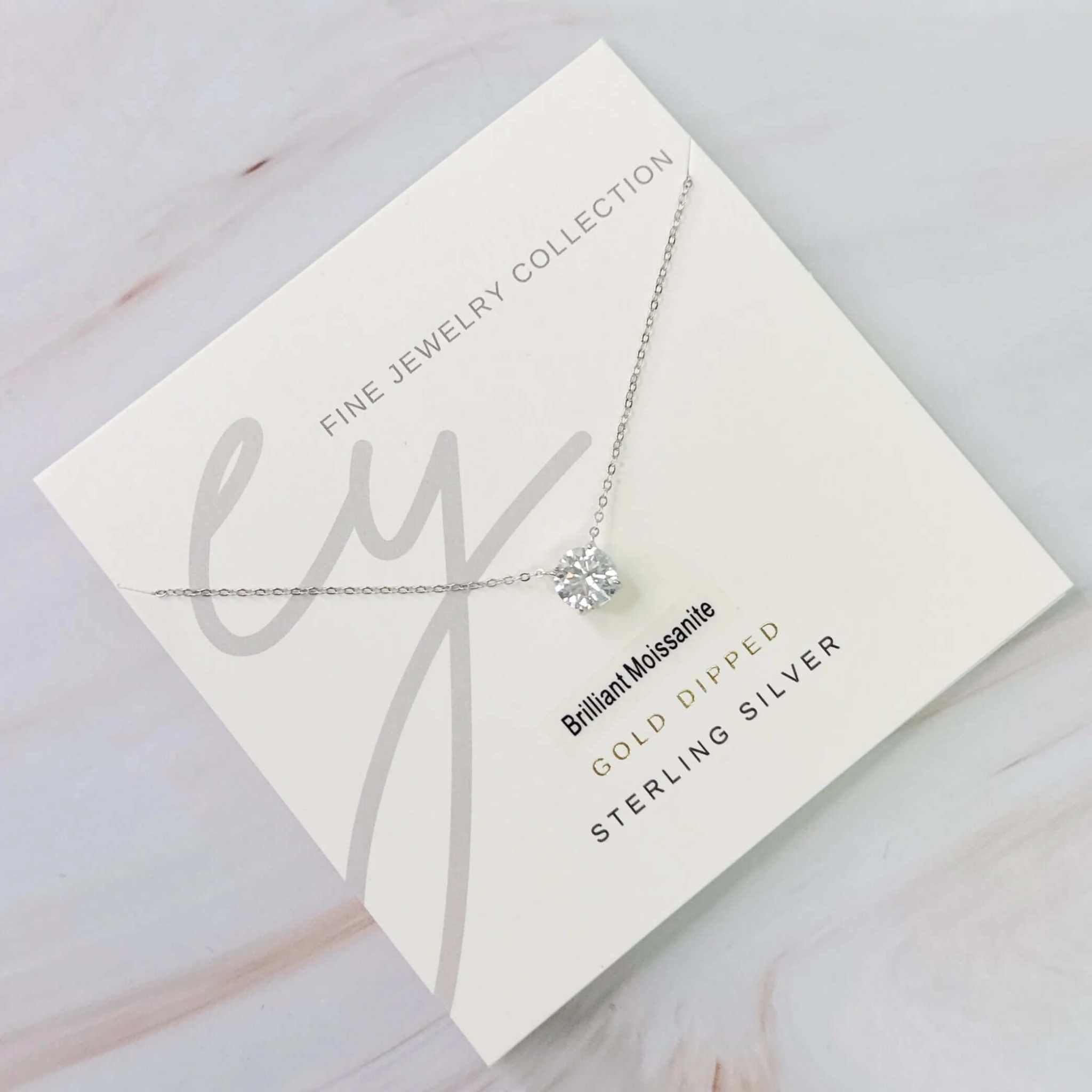 Brilliant Moissanite floating pendant necklace on a presentation card, featuring gold dipped and sterling silver details.