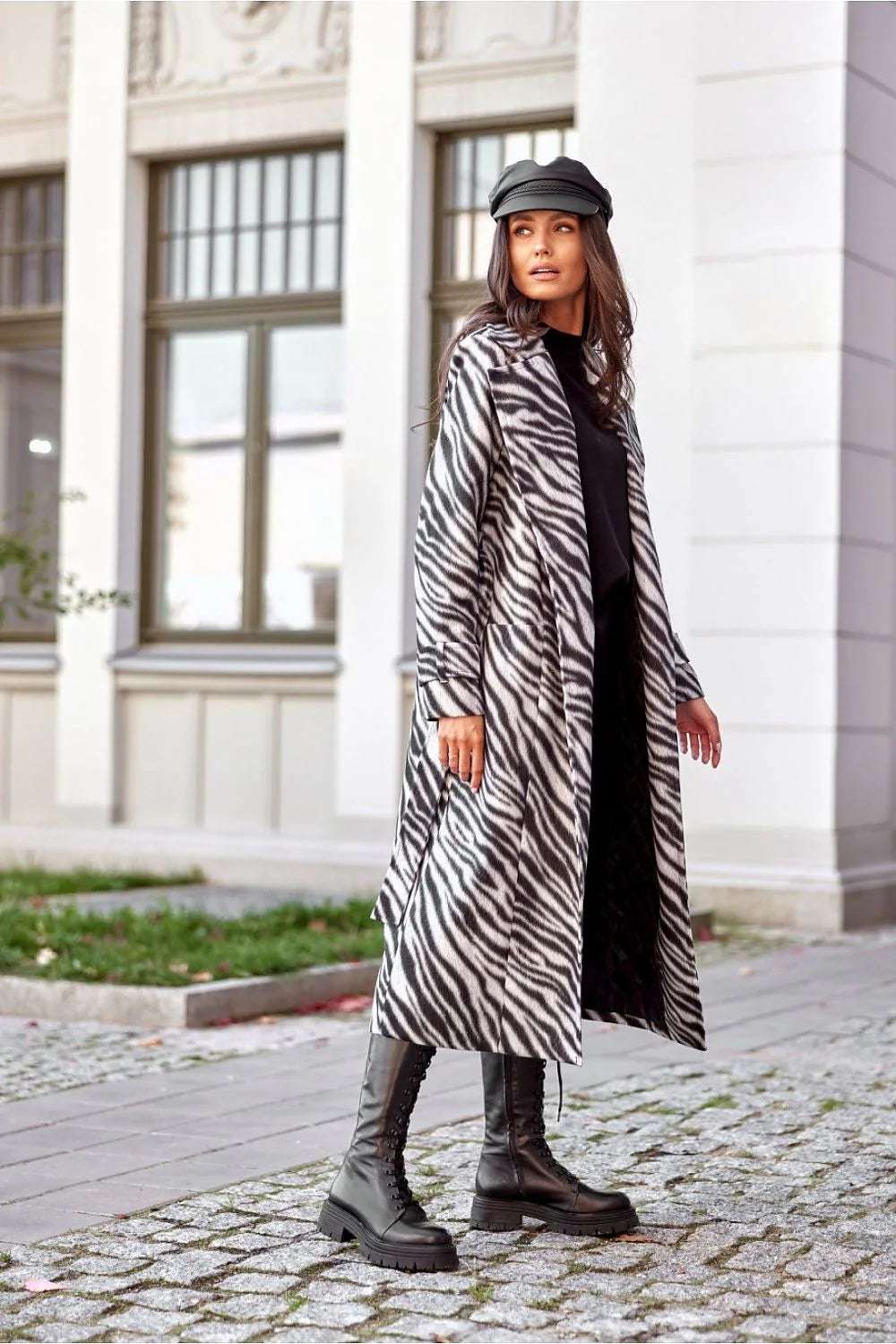 Chic Roco Inspired Longline Coat in zebra print worn by a model, paired with a cap and trendy knee-high boots.