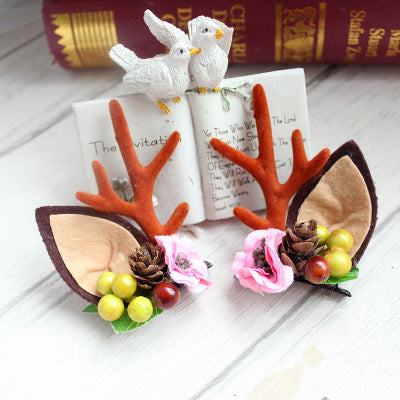 Children's Christmas hair clip with fabric antlers, pinecone, and floral decorations