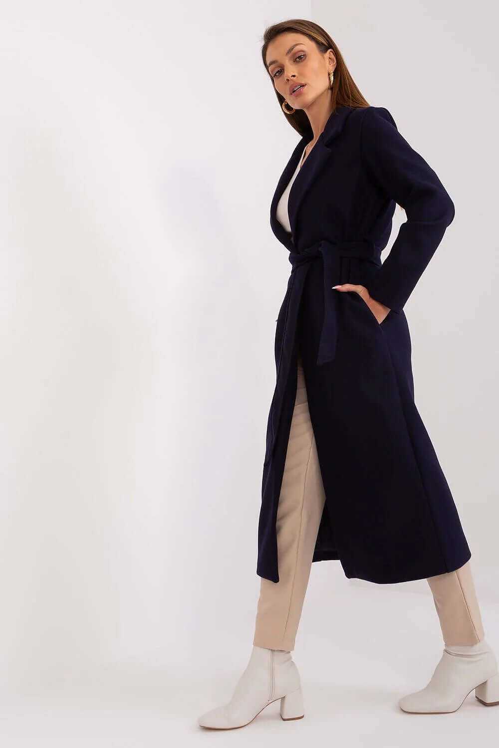 Model wearing a long navy wool blend coat with a belt, styled with light pants and ankle boots.