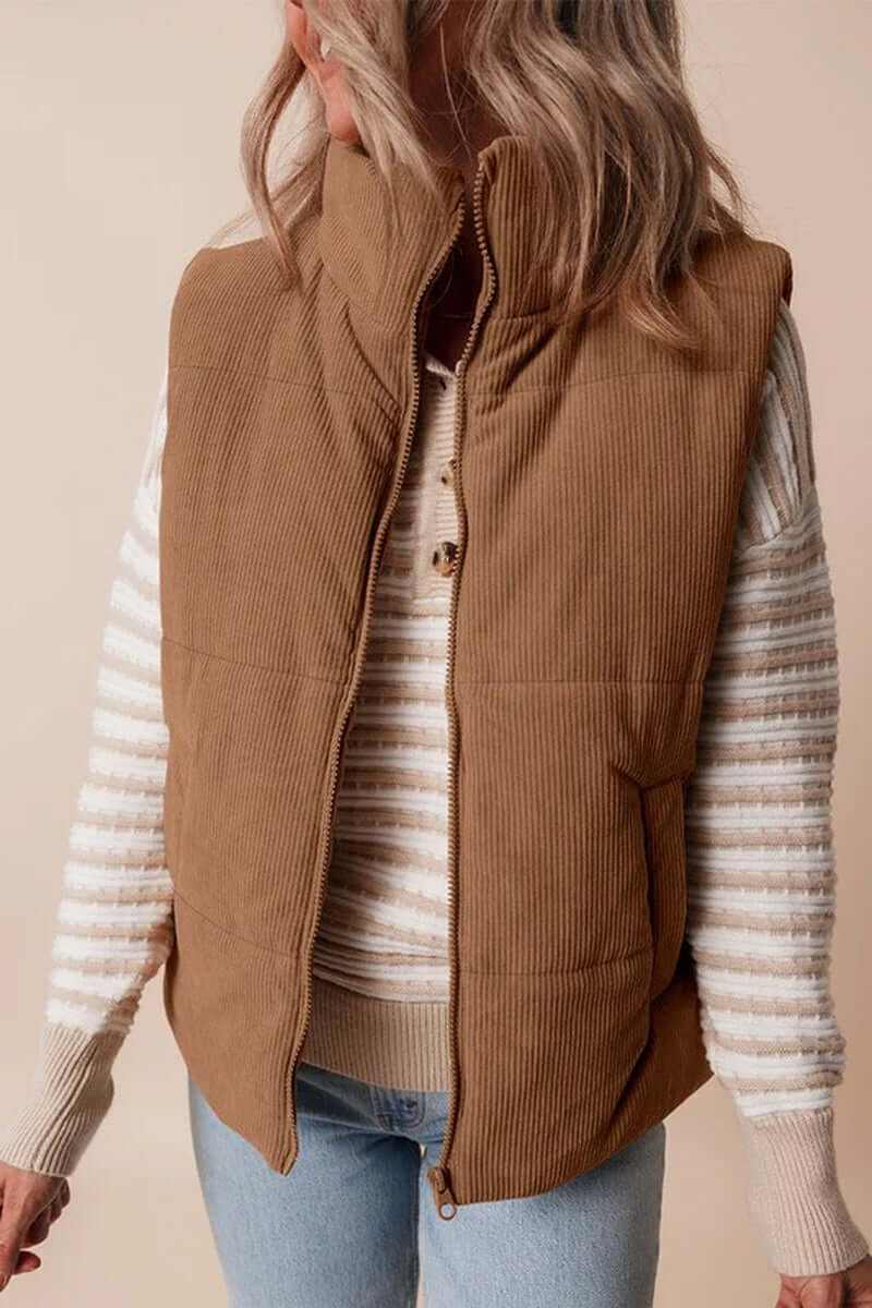 Coffee corduroy puffer vest with stand neck and zipper closure, styled with a striped sweater.