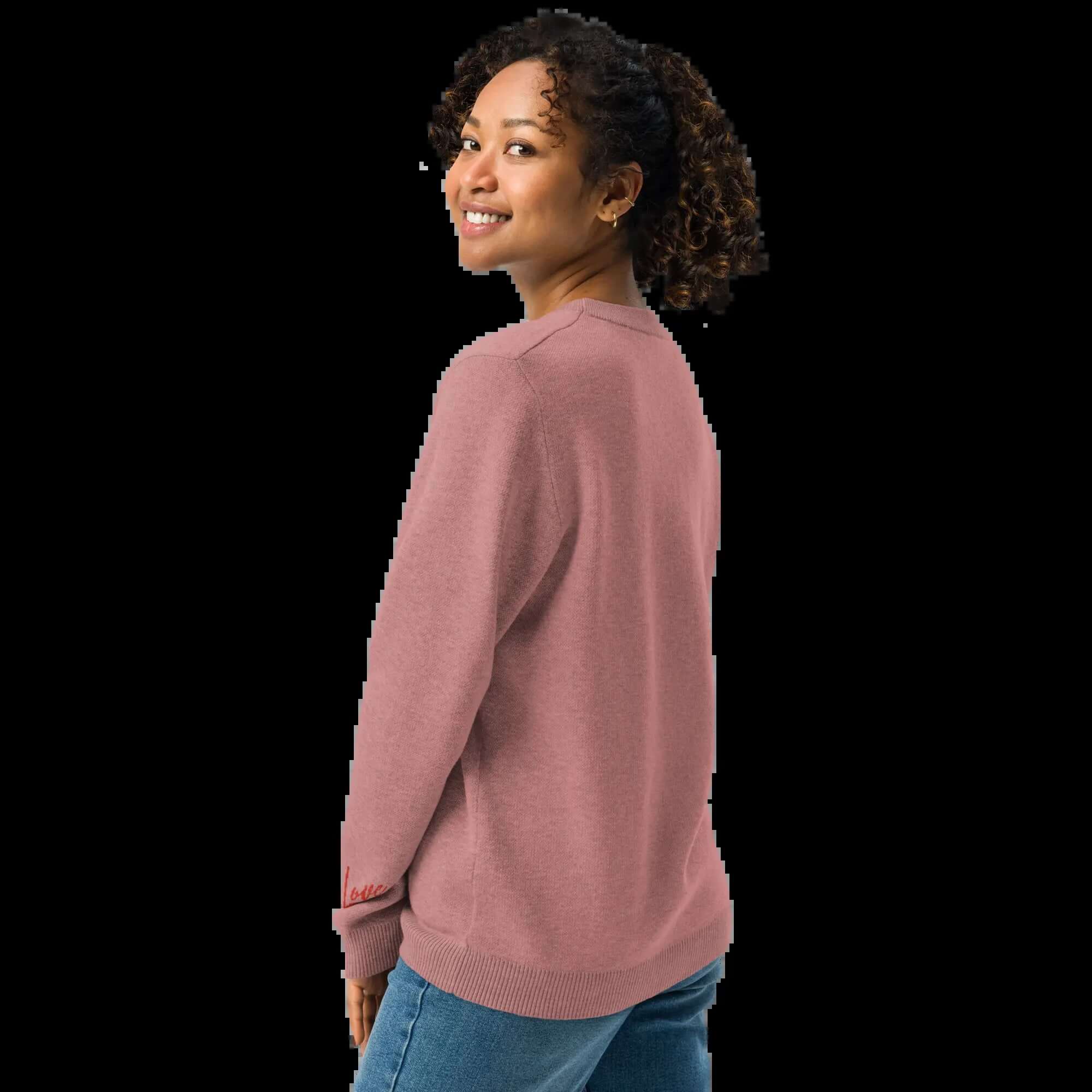 Woman wearing a cozy coral heart knit crewneck sweater from the back, showcasing its soft fabric and relaxed fit.