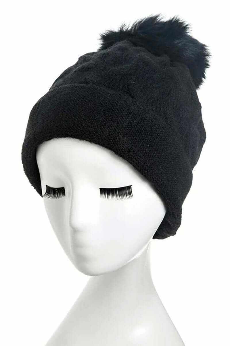 Cuffed slouchy beanie with fur pom on a mannequin head, showcasing cozy knit material and stylish design.