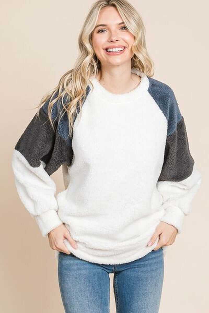 Smiling woman wearing a Culture Code Color Block Faux Fur Raglan Sleeve Sweatshirt with blue and gray sleeves.