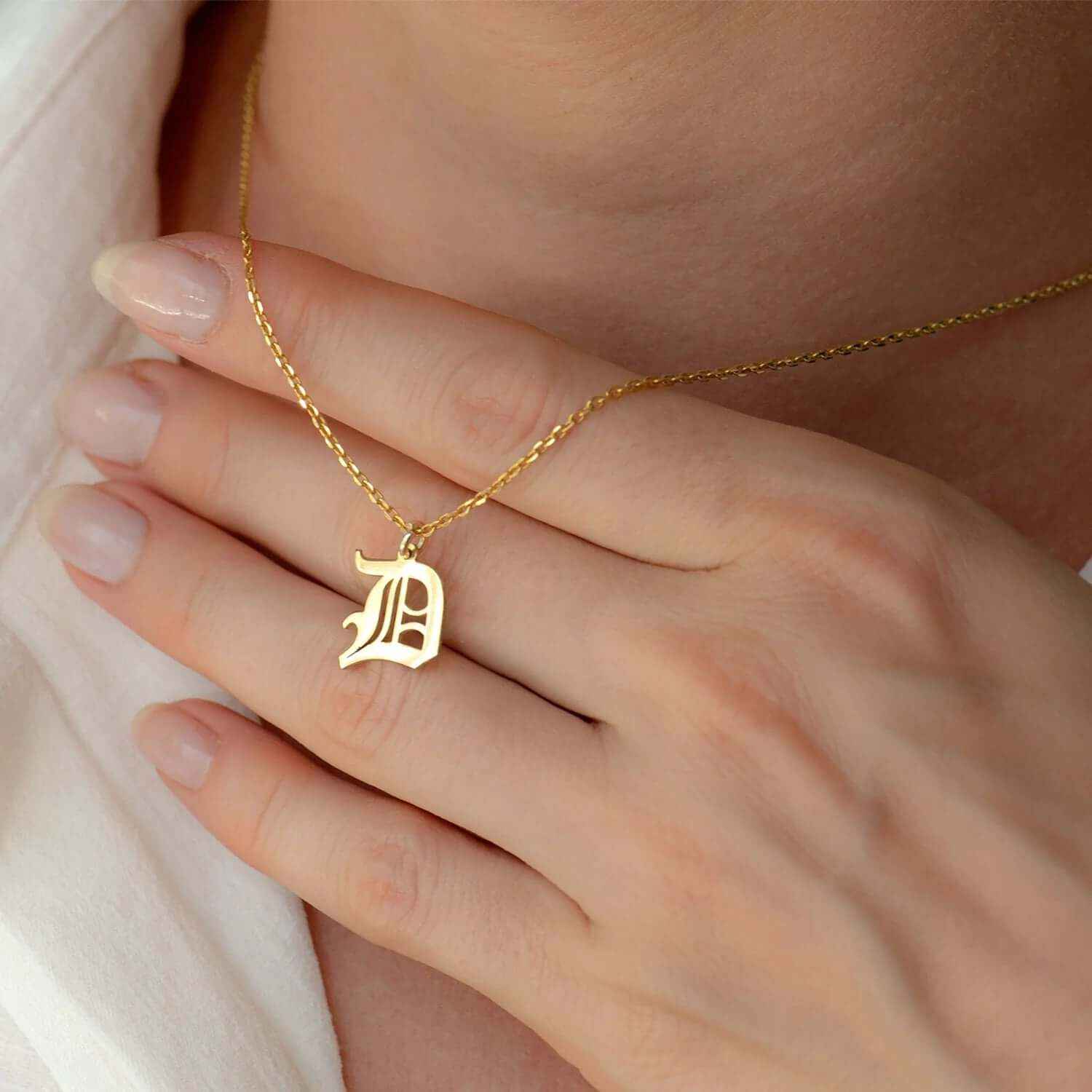 Custom Gothic letter 'D' initial necklace, 18K gold plated, worn on a delicate chain, showcasing minimalist elegance.